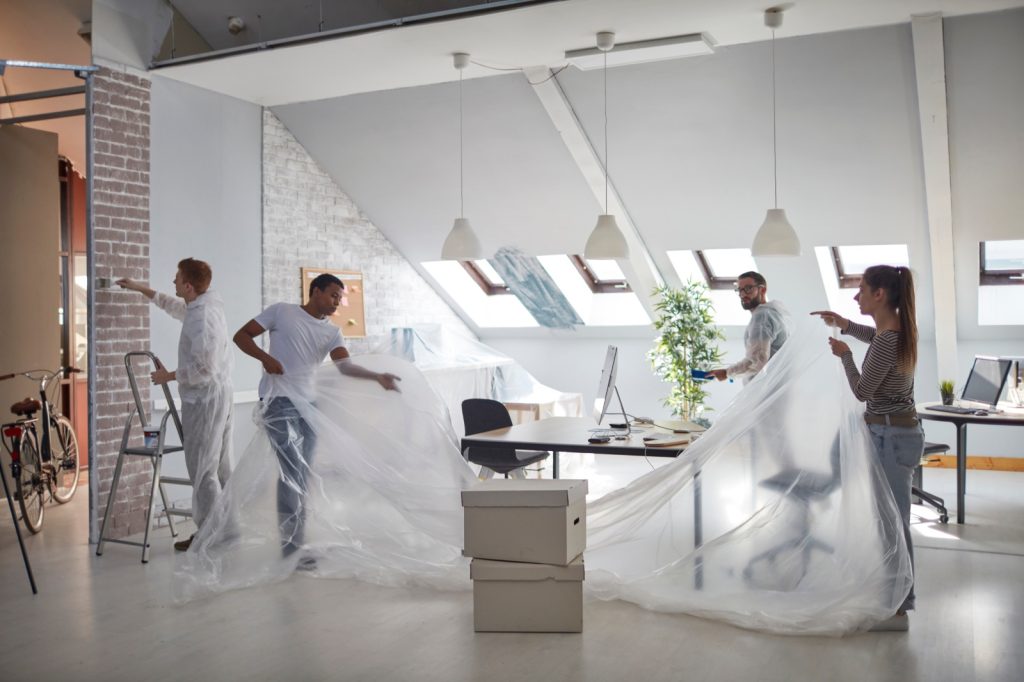 Team medewerkers bereidt kantoorruimte voor op renovatie met beschermfolie en schilderwerken.