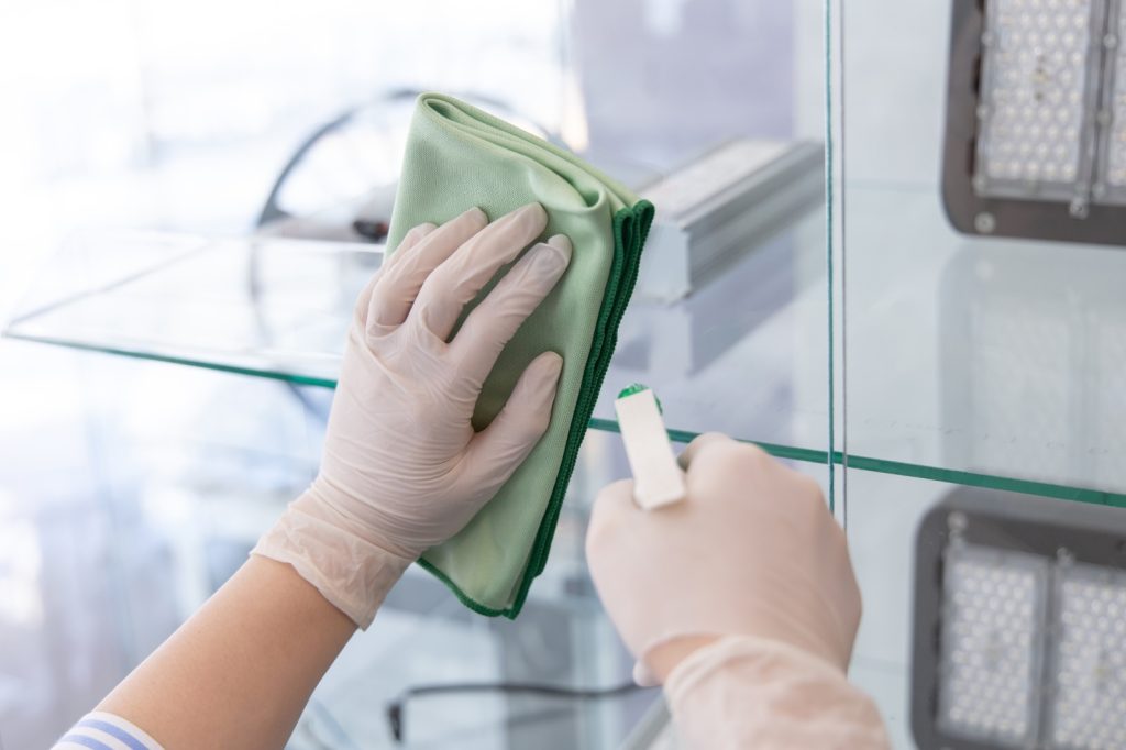 Glazen plank wordt schoongemaakt met een microvezeldoek.