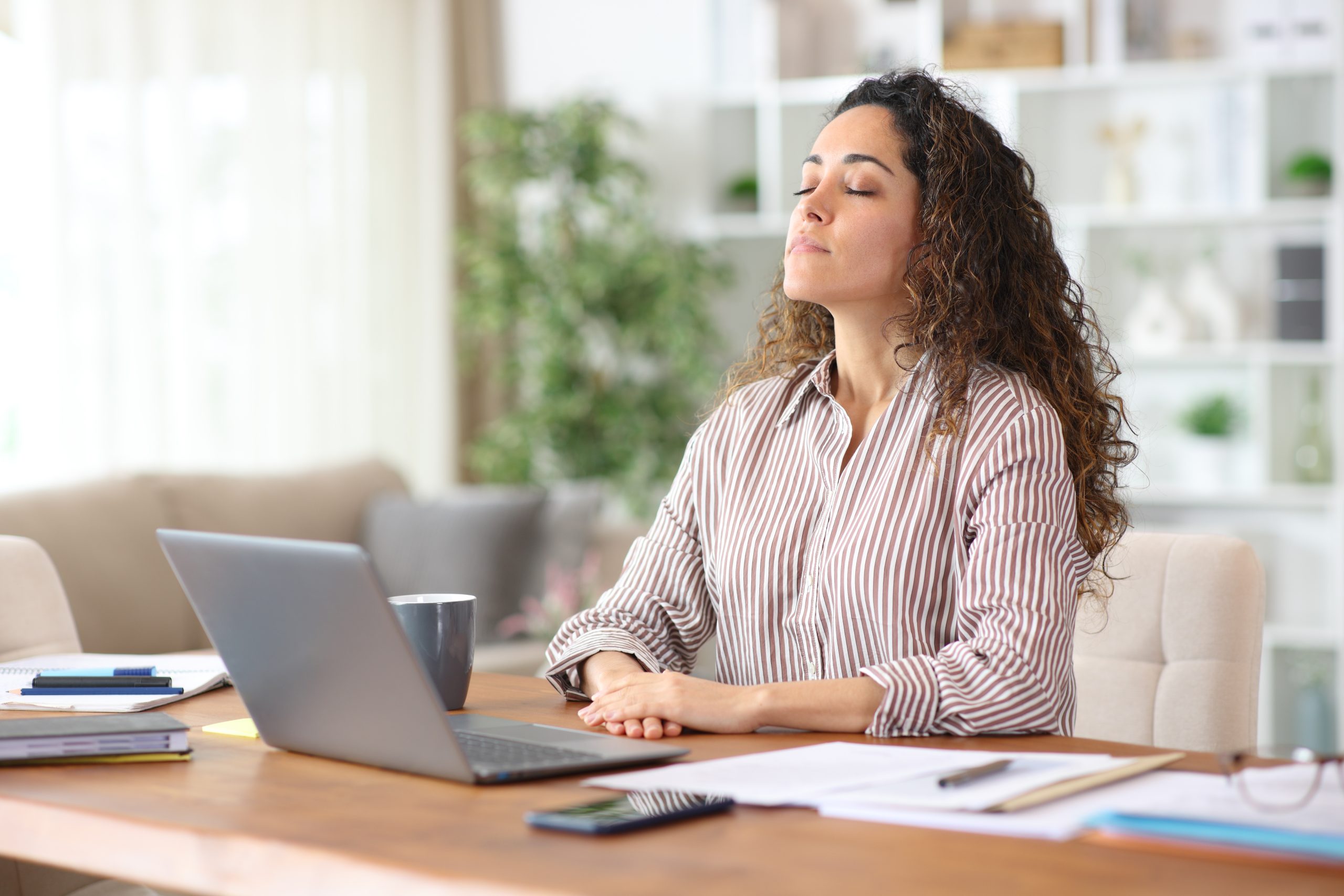 Medewerker ademt bewust frisse lucht in op kantoor — goede luchtkwaliteit verhoogt welzijn en productiviteit.