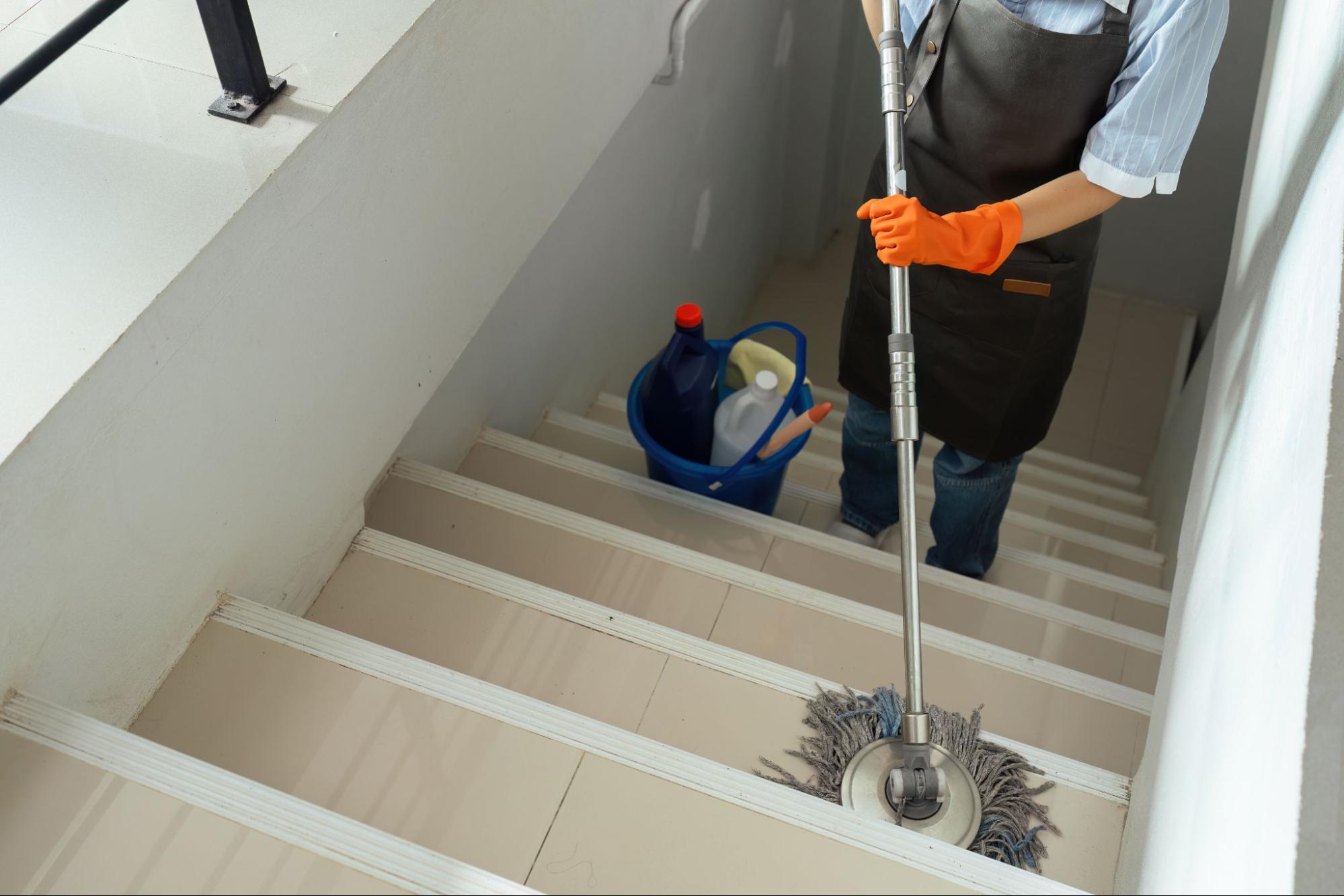 Schoonmaker dweilt de trappen en gangen van een schoolgebouw tijdens de zomerschoonmaak