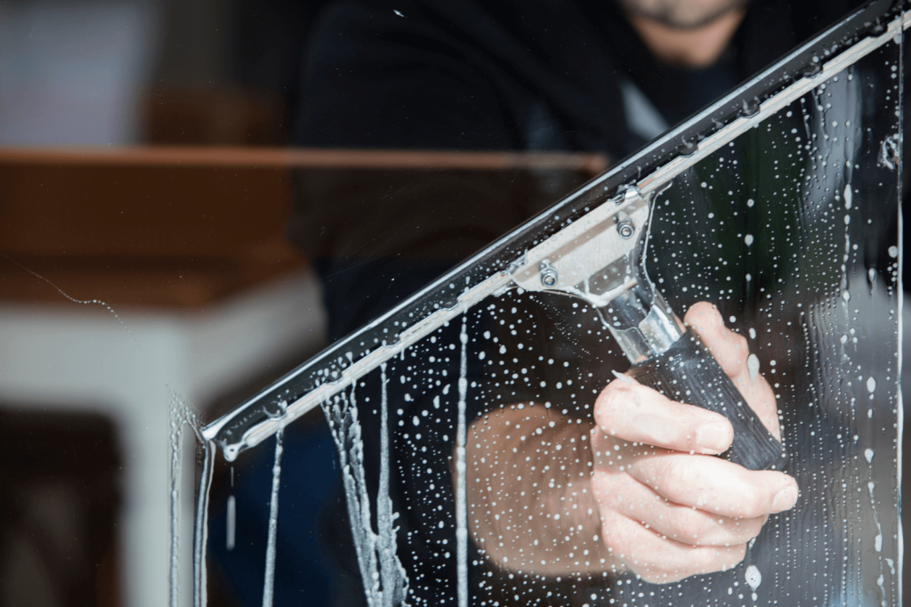 Ramenwasser trekt met een wisser een bedrijfsraam schoon en streeploos