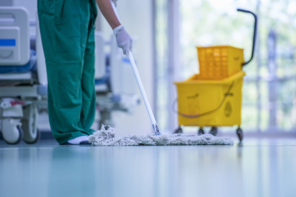 Schoonmaker dweilt professioneel een glanzende vloer in een zorginstelling